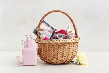 Dekoratif kozmetik ürünleri, Paskalya yumurtaları ve beyaz arka planda çiçekler olan hasır sepet.