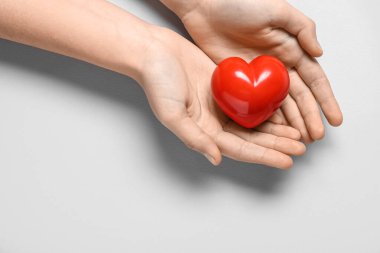 Gri arka planda kırmızı kalpli kadın elleri