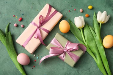 Paskalya yumurtaları hediye kutuları ve yeşil grunge arka planda lale çiçekleri.