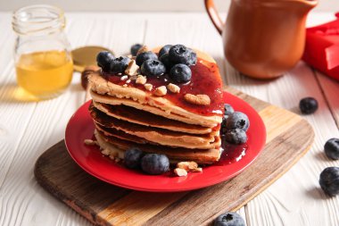 Kalp şeklinde leziz gözlemeler, hafif ahşap arka planda yaban mersini ve reçel, yakın plan. Sevgililer Günü kutlaması