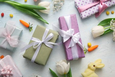 Hediye kutularıyla Paskalya tavşanı ve mavi grunge arka planında lale çiçekleri.