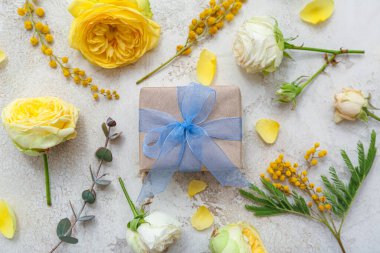 Zarif paketlenmiş hediye kutusu ve arka planda bahar çiçekleri dekoru