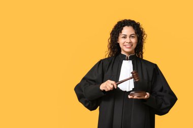 Sarı arka planda tokmağı olan güzel, mutlu, Afro-Amerikan kadın yargıç.