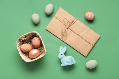 Boyanmış yumurta sepeti, Paskalya tavşanı ve yeşil arka planda zarf. Üst görünüm