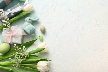 Çiçekli Paskalya yumurtaları, hediye kutuları ve grunge mavisi arka planda bir tavşan.