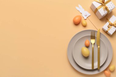 Turuncu arka planda hediyeler, yumurtalar ve tavşanlarla dolu güzel bir Paskalya masası.