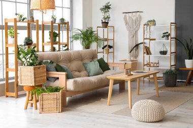 Rahat kanepesi, masası, çiçekleri, rafları ve penceresi olan şık bir oturma odası.