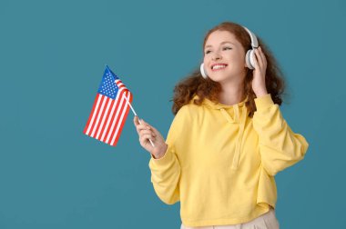 Mavi arka planda Amerikan bayrağı olan kulaklıklı genç bir kadın.