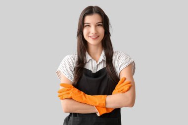 Gri arka planda lastik eldivenli genç kadın.