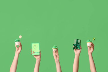 Lezzetli kekleri olan kadın eller, hediye kutusu ve yeşil arka planda Aziz Patrick Günü için neşeli kartpostal.