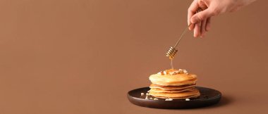 Bal kaplamalı el ve bal kabaklı krep yığınıyla bej arkaplan ve metin için boşluk