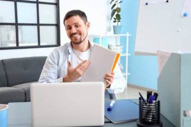 Male tutor with notebook giving online lesson at home