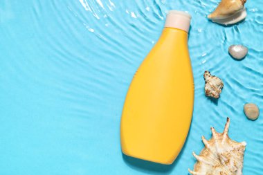 Deniz yıldızlı güneş kremi ve deniz kabukları renkli arka planda.