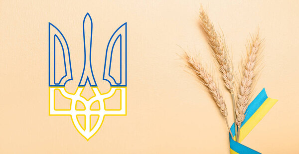 Wheat spikelets and ribbons in colors of Ukrainian flag with coat of arms on beige background