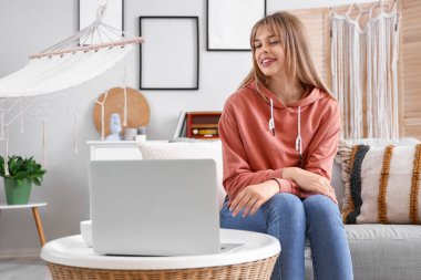 Evde dizüstü bilgisayarı olan genç bir kız sohbet ediyor.