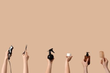 Bej arka planda farklı kuaför malzemeleri olan bir sürü el.