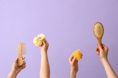 Leylak arka planında farklı kuaför malzemeleri olan bir sürü el.