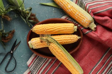 Mavi masada taze mısır koçanları olan bir kase.