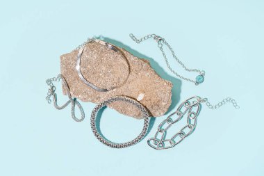 Mavi arka planda farklı gümüş bilezikleri olan rock.