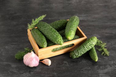 Siyah arka planda taze salatalıklı ahşap kutu.