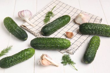 Beyaz ahşap arka planda taze salatalık, sarımsak ve dereotu.