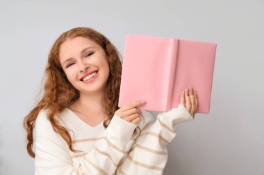 Işık arkaplanı üzerine kitap okuyan genç bir kadın.