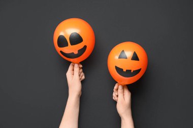 Siyah arka planda komik Cadılar Bayramı turuncu balonları olan kadın elleri