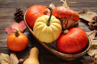 Taze balkabakları ve ahşap arka planda sonbahar yapraklarıyla hasır kase.