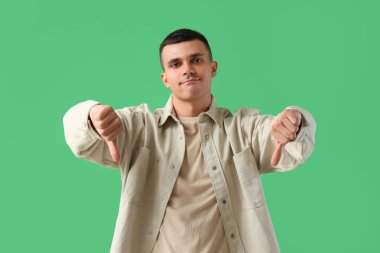 Yeşil arka planda hoşnutsuzluk gösteren genç bir adam