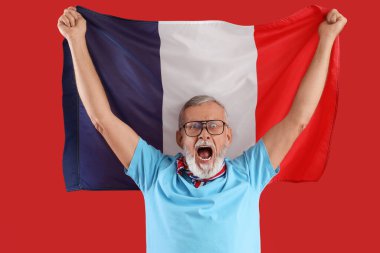 Kırmızı arka planda Fransa bayrağı taşıyan kıdemli adam.