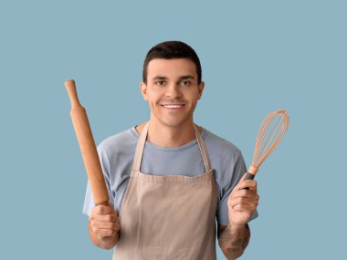 Mavi arka planda merdanesi ve çırpısı olan yakışıklı, mutlu aşçı.