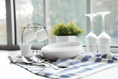 Mutfaktaki pencerenin yanındaki masada temiz tabaklar var.