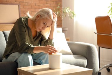 Depresif Olgun kadın evde koltukta oturan