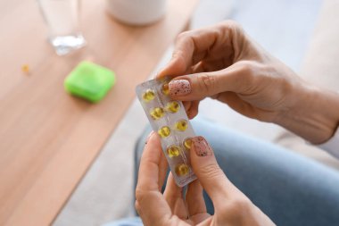 Olgun bir kadın elinde haplarla geziyor, yakın plan.