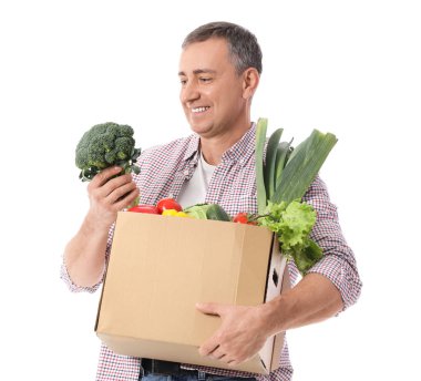 Beyaz arka planda bir kutu taze sebzeli olgun adam.