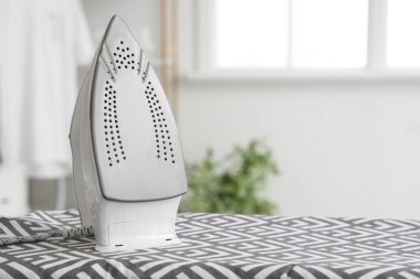 Çamaşır odasında modern demirle ütü tahtası, yakın plan.