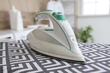 Çamaşır odasında modern demirle ütü tahtası, yakın plan.