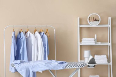 Askısı, rafı ve ütü masası olan çamaşır odasının içi.