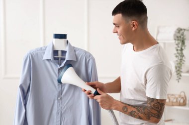 Evdeki mavi gömlekli mutlu genç adam.