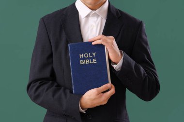 İncil 'i olan genç adam yeşil arka planda dua ediyor, yakın plan