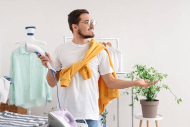 Buharlı mutlu genç adam çamaşır odasında bir şeyi işaret ediyor.