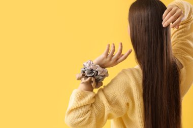 Sarı arka planda ipek tokaları olan güzel genç bir kadın.