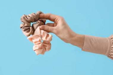 Mavi arka planda ipek tokaları olan kadın eli