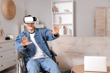 Evde VR gözlüğü kullanan tekerlekli sandalyedeki mutlu genç adam.