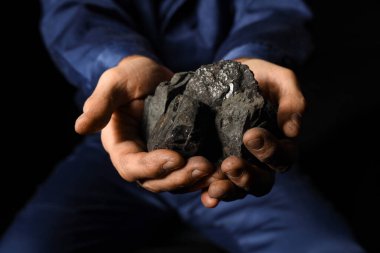 Siyah arka planda kömürü olan olgun madenci, yakın plan.