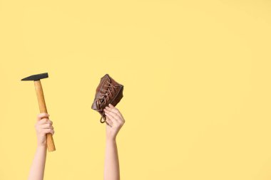 Ayakkabı parçalı kadın eller ve sarı arka planda çekiç. Ayakkabı tamir konsepti