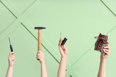 Ayakkabı parçalı kadın eller ve yeşil ahşap arka planda el aletleri. Ayakkabı tamir konsepti