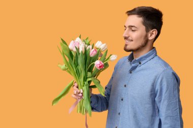 Sarı arka planda güzel lalelerle dolu bir buketi olan genç adam. Uluslararası Kadınlar Günü