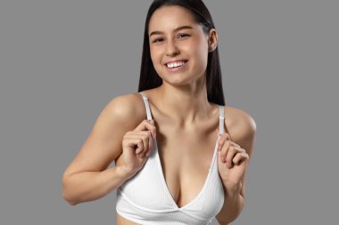 Gri arka planda beyaz pamuklu iç çamaşırlı zayıf genç bir kadın.