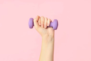 Pembe arka planda dambılı kadın eli, yakın plan.